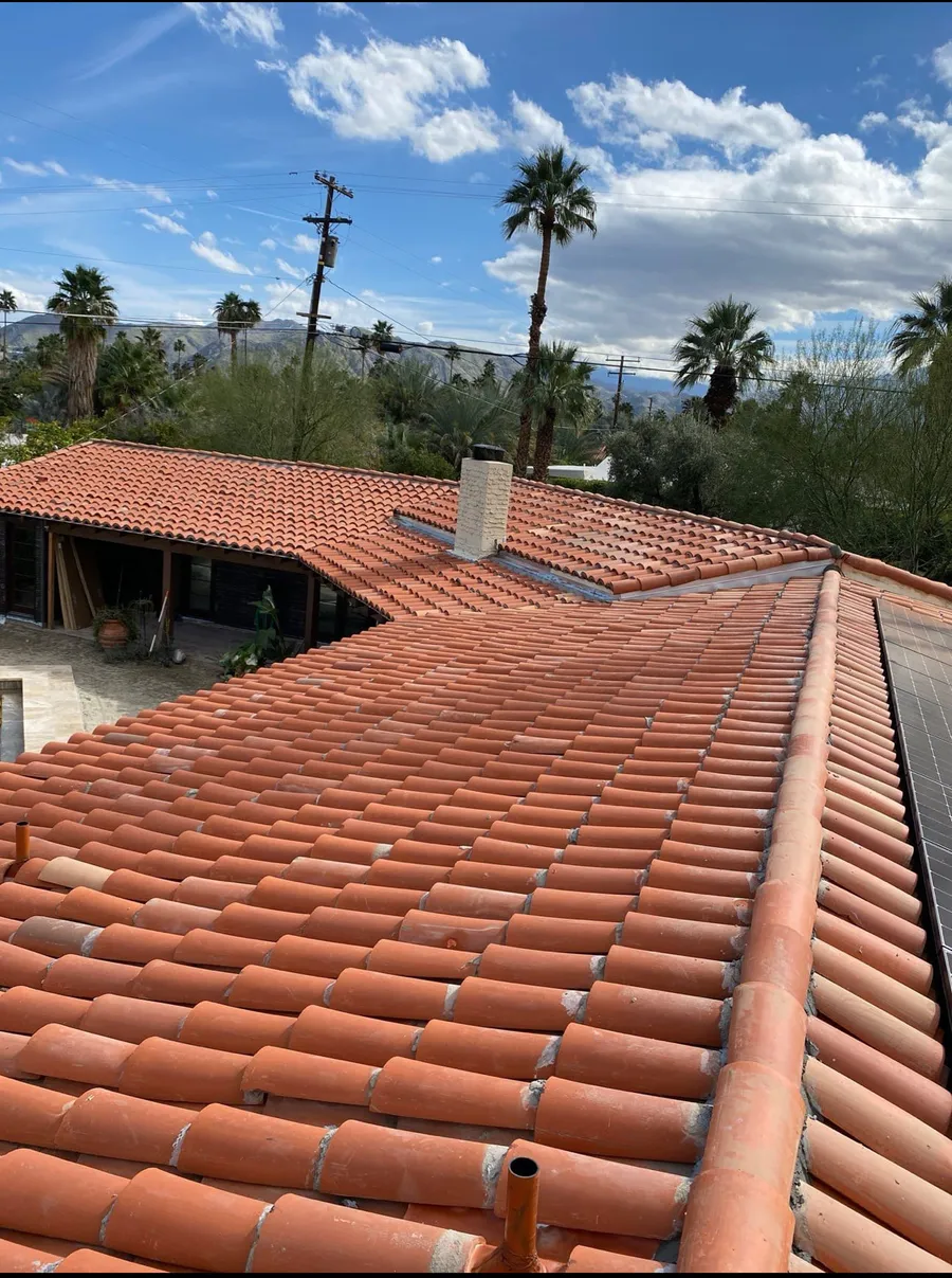 Terracotta barrel tile running in even courses down a desert home, palms and a covered patio below