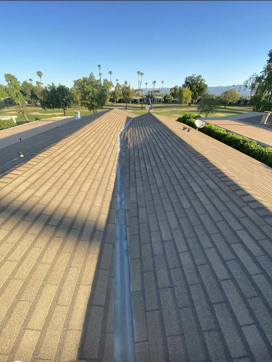 A gold-toned shingle roof and its ridge line, a golf course green behind