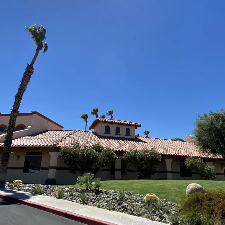 A tile-roofed home from the street, palms and desert planting in front