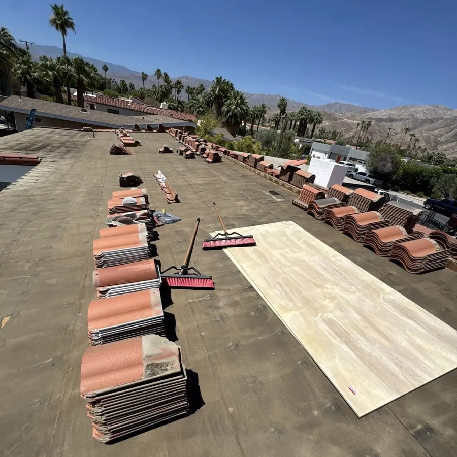 Stacks of terracotta tile and hand tools set out on a flat roof during a re-roof